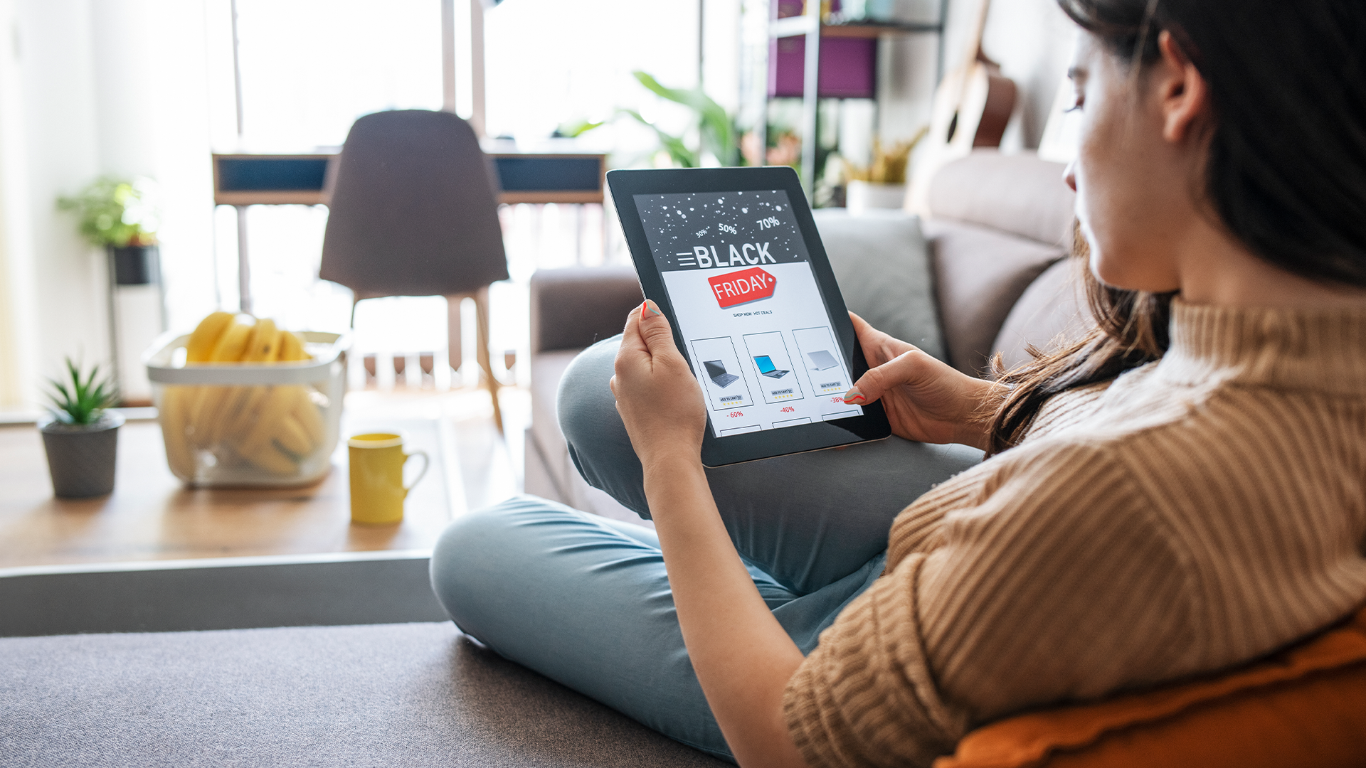 Woman sitting on her couch browsing holiday sales