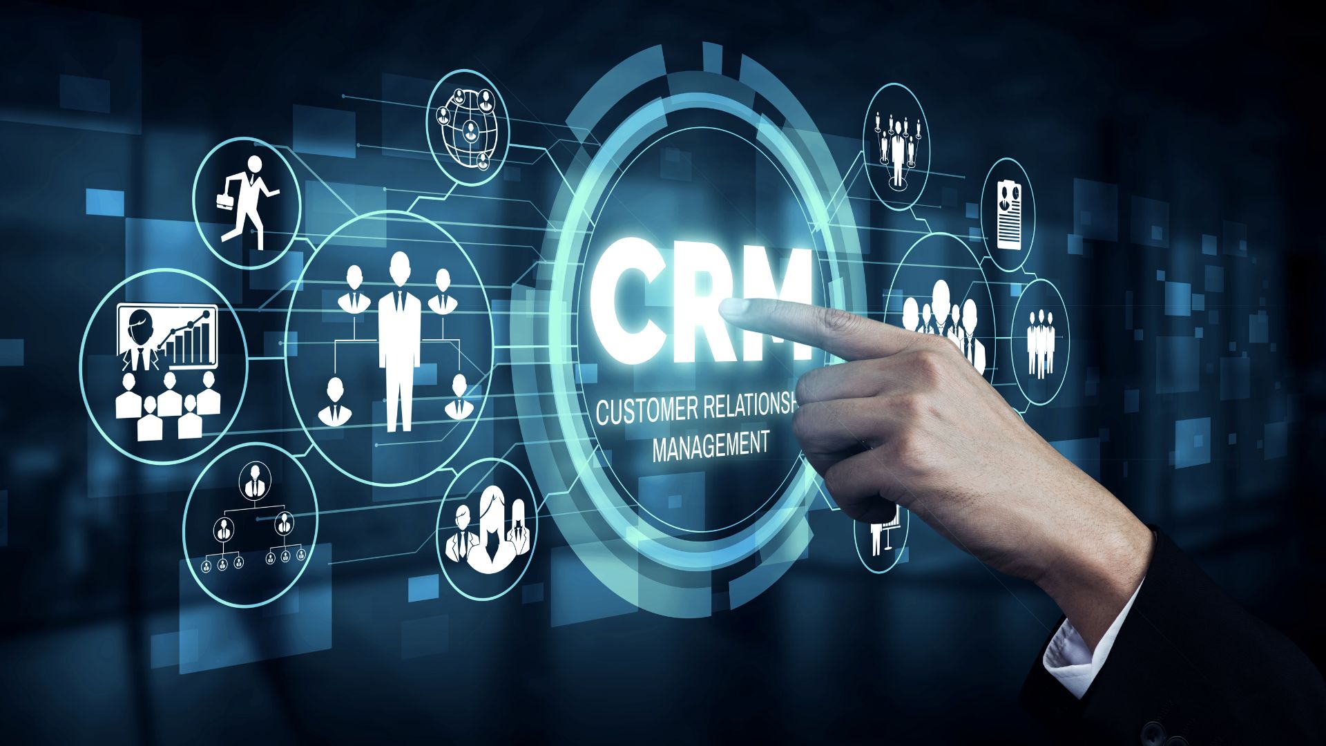 Businessman pointing at a glowing holographic "CRM — Customer Relationship Management" interface, surrounded by connected circular icons representing people, teams, analytics, and business networks against a dark blue tech background.